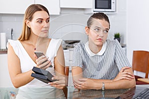 Girl showing smartphone to her unhappy friend