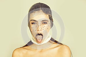 Girl showing tongue with white, fishnet stocking on head