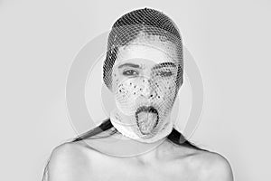 Girl showing tongue with white, fishnet stocking on head
