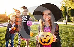 Girl showing trick or treat basket near friends