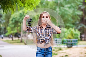 The girl shows an air kiss that the grapes are delicious. Beautiful little farmer girl eating organic grapes. The concept of harve