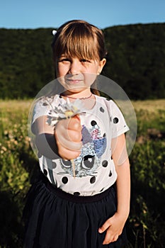 Girl shows bouquet of flowers that she holds in her hand. Small five year old Caucasian girl with beautiful long hair stands at