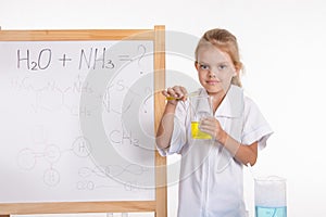 Girl shows chemical experience standing at the blackboard