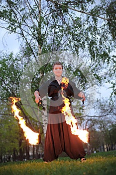 A girl shows a fire show on nature