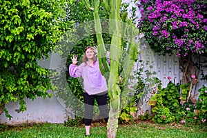 Girl shows hands from behind a tall cactus