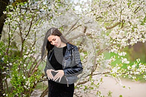 The girl shows the heart on the belly of a pregnant woman. Beautiful pregnant woman loves a child, making a heart shape on her