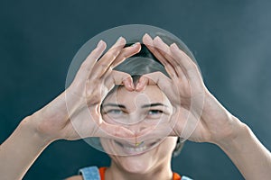 The girl shows a heart folded from her fingers and smiles