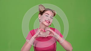 Girl shows the heart shape with her hands. Green screen. Slow motion