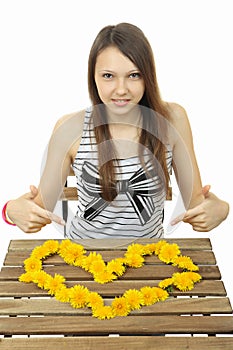 Girl shows the heart of wildflowers. Heart of yellow dandelions.