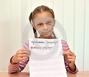 The girl shows a leaf of a calligraphical copy-book with words. The Russian text - copy-books, an ostrich