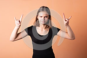 A girl shows a rocker goat, on a light orange background