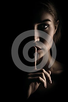The girl shows a sign of silence. Face on black background