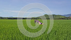 Girl Shows Yoga Pose on Green Rice by Hills