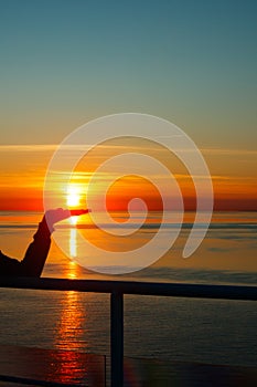 Girl silhouette with sun on the palm in magical sunset over the Gulf of Finland, Baltic sea