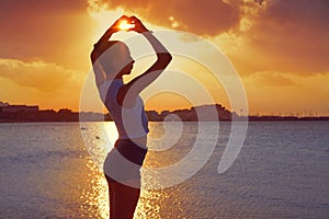 Girl silhouette at beach sunset heart shape