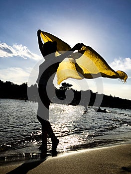 Girl silhouette with yellow scarf under sunset