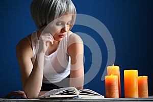 Girl in silver wig and white singlet reading the book. Close up. Blue background