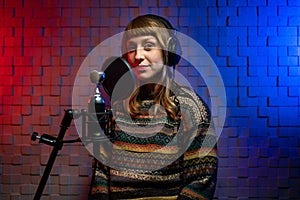girl singer in headphones, sweater in recording studio with microphone