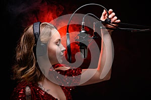 Girl singer sings into a microphone, with a spectacular background, vocals, recording studio, recording a track