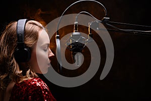 Girl singer sings into a microphone, with a spectacular background, vocals, recording studio, recording a track photo
