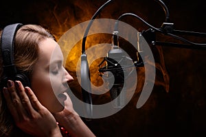 Girl singer sings into a microphone, with a spectacular background, vocals, recording studio, recording a track photo