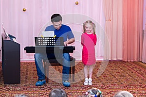 Girl sings while her father plays synthesizer