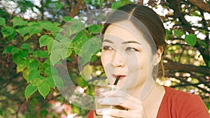 Girl sipping ice coffee through a straw of a glass with mean and sneaky eyes and naughty smile. Flirting behaviour of