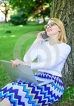 Girl sit grass with notebook. Woman with laptop in park order item on phone. Girl takes advantage of online shopping