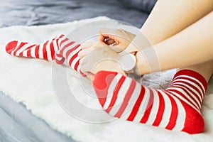 The girl sit on a white carpet and put on socks, white punctuate red side.
