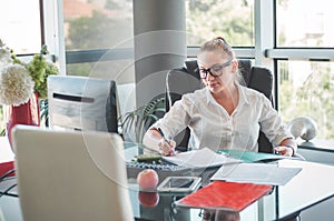 Girl siting in an office chair and checking contracts and documents. Office worker. Business woman.