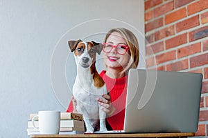 Girl sititng at table with computer and dog