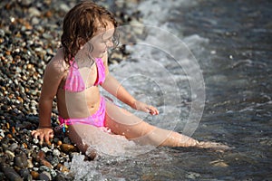 Girl sits ashore in waves