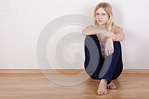 Girl sits with back pressed against wall