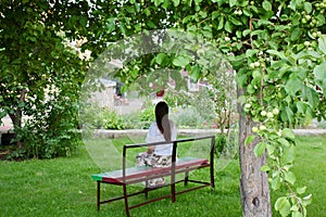 Girl sits on the bench under the apple tree Concept Relax Pacification