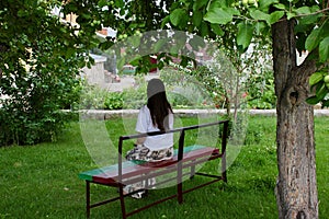 Girl sits on the bench under the apple tree Concept Relax Pacification