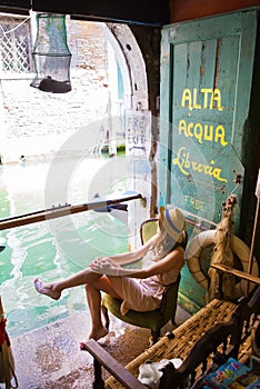 Girl sits in a bookstore on the water of Alta Acqua Libreria in Venice, Italy