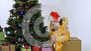 Girl sits on a box near the Christmas tree after the New Year holidays and misses