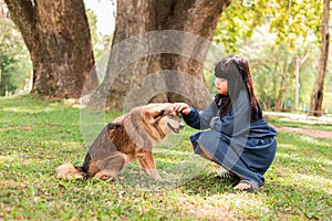 A girl sits with a brown dog in the garden.