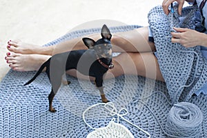 The girl sits on the carpet and knits