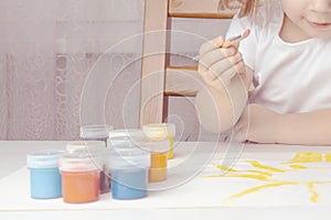 a girl sits on a chair and paints the sun with a brush with yellow paint