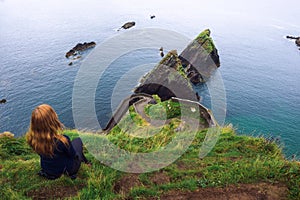 Girl sits on a cliff over the ocean in Ireland photo