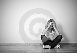 Girl sits in a depression on the floor near the wall