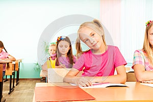 Girl sits at desk with elbows on exercise book photo