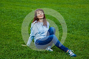 the girl sits on the field and the wind blows her hair