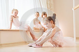 Girl sits on the floor. Little ballerinas preparing for performance by practicing dance moves