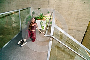 Girl sits on floor near pot with green plants