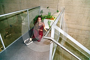 Girl sits on floor near pot with green plants