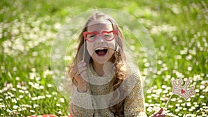 Girl sits on grass at grassplot, green background. Child girl spend leisure outdoors. Best holiday concept. Child posing