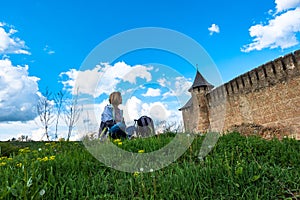 A girl sits on the grass near the ancient fortress, Khotyn Ukraine