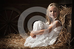 Girl sits on hay in the barn